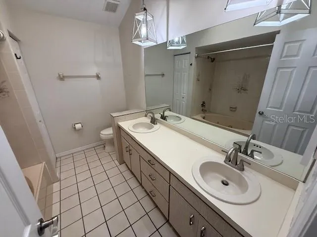 a spacious bathroom with a double vanity sink a toilet and a mirror