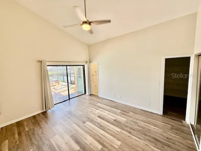 an empty room with wooden floor fan and windows