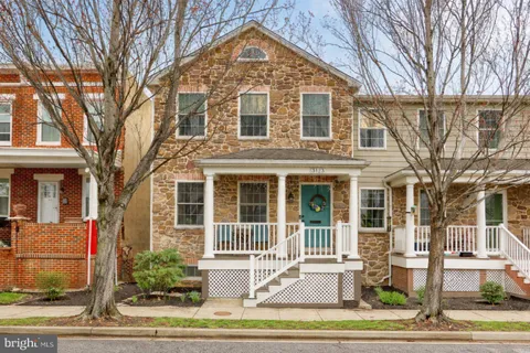 a view of a brick house with a yard plants and large tree