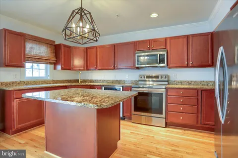 a kitchen with stainless steel appliances granite countertop a sink dishwasher stove and cabinets with wooden floor