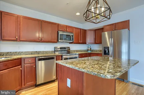 a kitchen with stainless steel appliances granite countertop a refrigerator a stove top oven a sink dishwasher and microwave with wooden floor