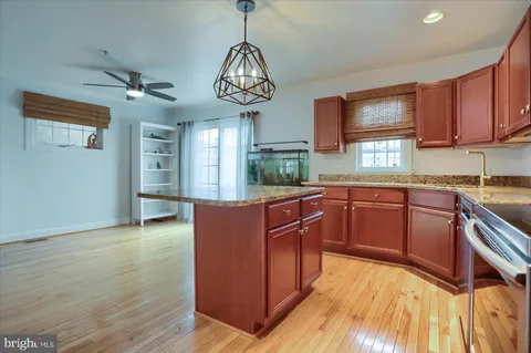 a kitchen with stainless steel appliances granite countertop wooden cabinets a dining table and chairs
