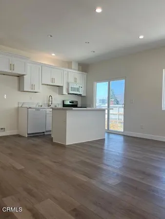 a large kitchen with wooden floors and white stainless steel appliances