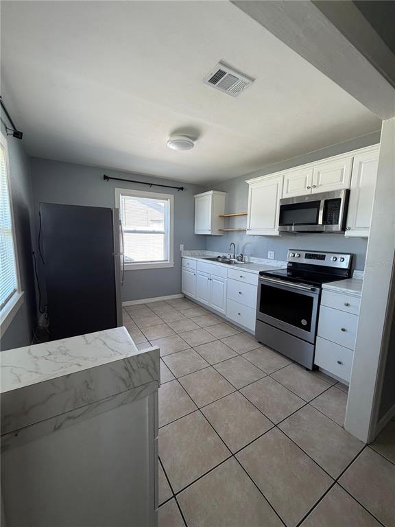 1111 Jersey Avenue St. Cloud, FL 34769 - Photo 9 of 11 a kitchen with stainless steel appliances kitchen island granite countertop a stove a sink and a microwave