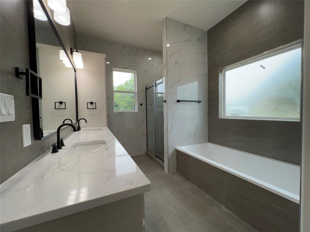 121 Cartwright Park Road Weatherford, TX 76087 - Photo 10 of 17 Modern bathroom featuring a double vanity with integrated sinks and black fixtures, a built-in soaking tub, and a separate glass-enclosed shower