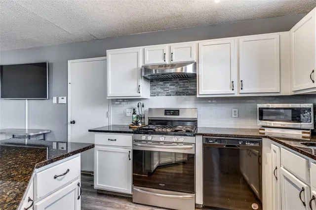 a kitchen with granite countertop a stove top oven microwave and cabinets