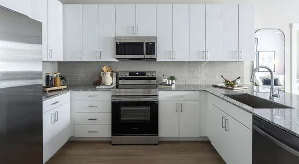 a kitchen with granite countertop white cabinets and stainless steel appliances