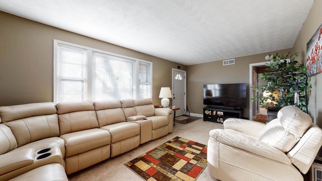 a living room with furniture a flat screen tv and a large window