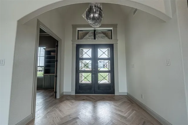 an empty room with chandelier fan and windows