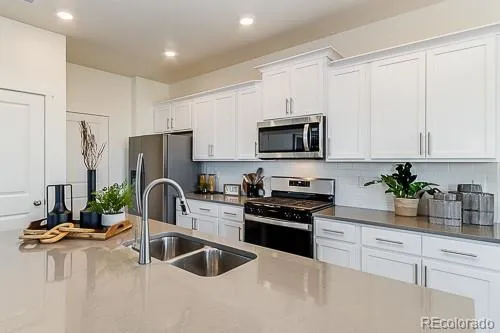 a kitchen with stainless steel appliances a stove a sink a refrigerator a stove a microwave and cabinets