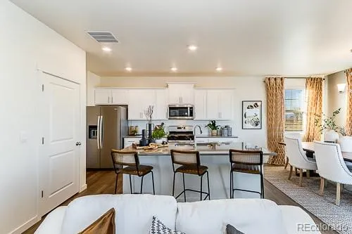 a view of kitchen with stainless steel appliances refrigerator stove dining table and chairs