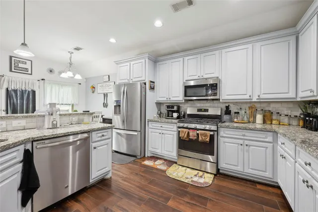 a kitchen with white cabinets and appliances
