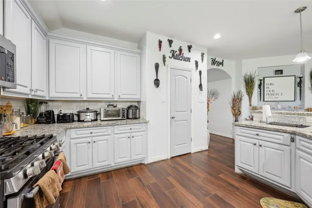 a kitchen with stainless steel appliances granite countertop a stove and white cabinets