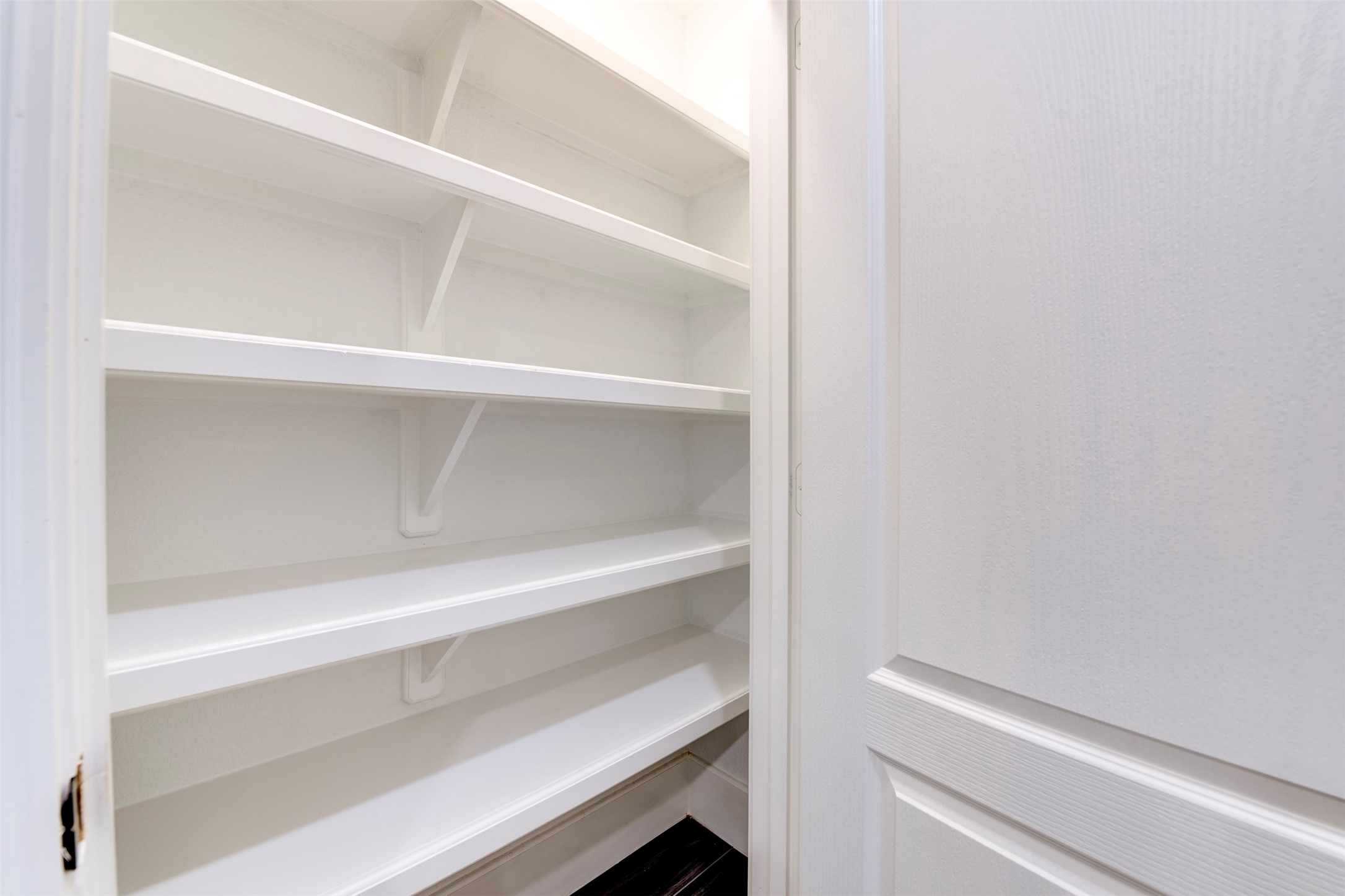 109 Dresden Street Houston, TX 77012 - Photo 23 of 43 This photo shows a small pantry with white built-in shelves, offering ample storage space for kitchen essentials.