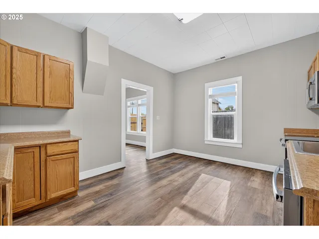a view of an empty room with window and wooden floor