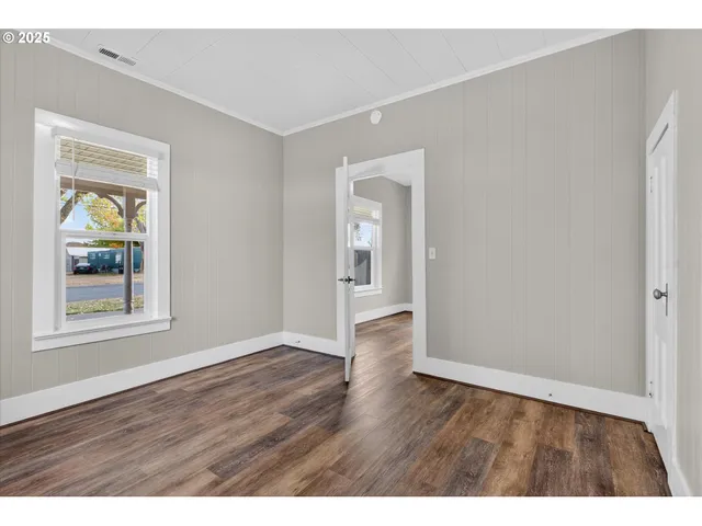 a view of an empty room with window and wooden floor