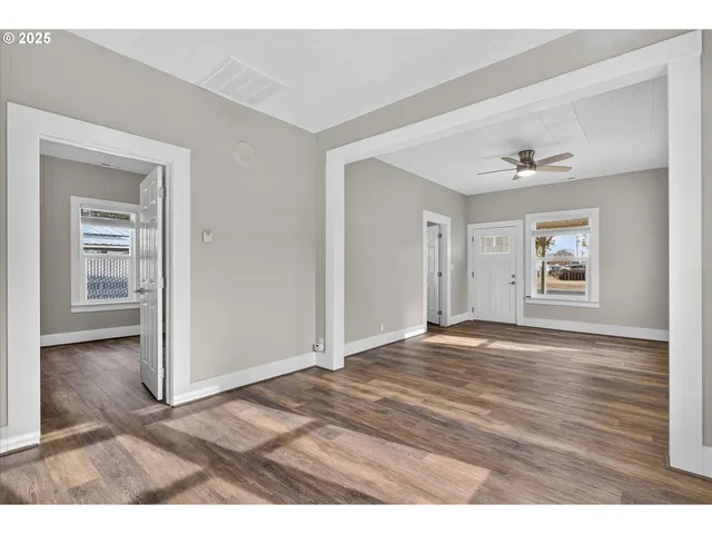 a view of an empty room with window and wooden floor
