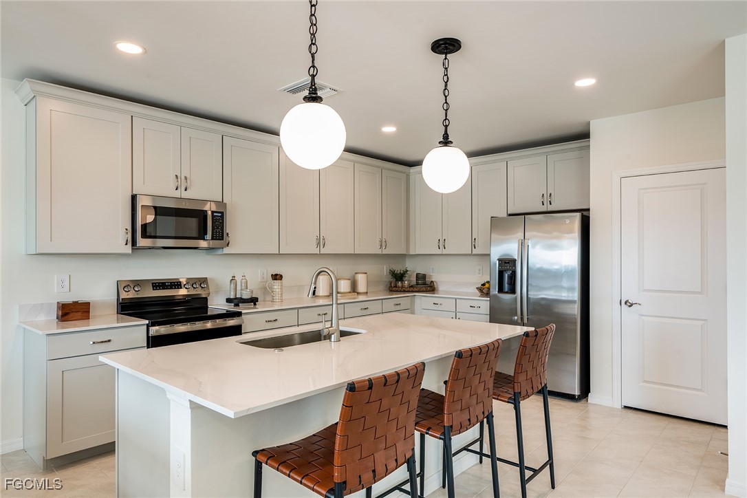 237 Moonlit Lk Trail Lehigh Acres, FL 33974 - Photo 4 of 18 a kitchen with stainless steel appliances a stove a refrigerator a sink a stove a dining table and chairs