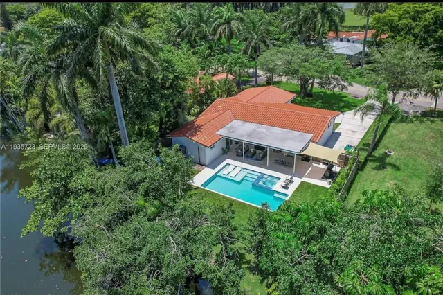 an aerial view of a house with garden space and trees all around