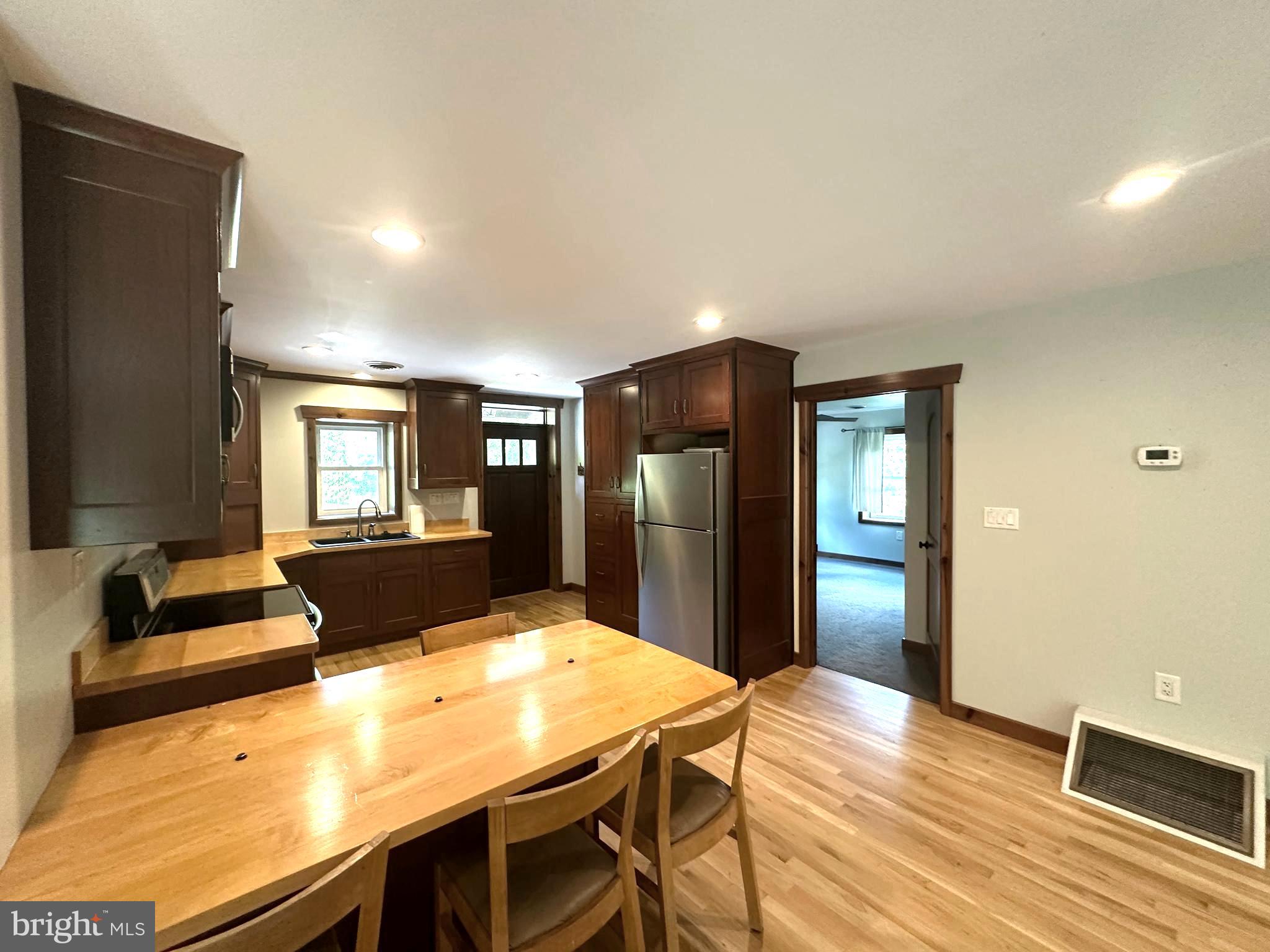3720 Basford Road Frederick, MD 21703 - Photo 8 of 38 a kitchen with stainless steel appliances kitchen island granite countertop a refrigerator a stove a sink dishwasher with a dining table and chairs with wooden floor