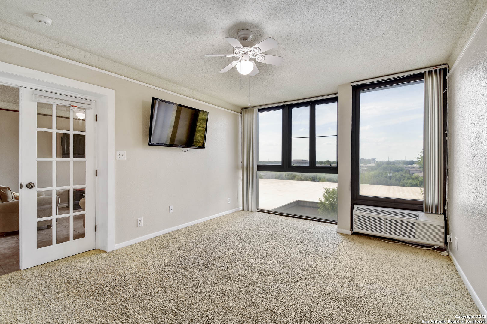 7701 Wurzbach Road, Unit 405 San Antonio, TX 78229 - Photo 14 of 42 an empty room with windows and ceiling fan