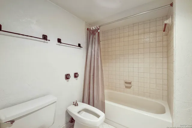 a bathroom with a shower a toilet and a bathtub