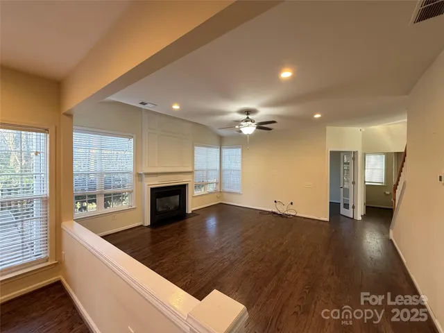 an empty room with wooden floor fireplace and windows