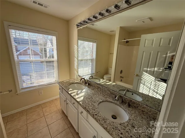a bathroom with a granite countertop sink a mirror a bathtub and next to a window