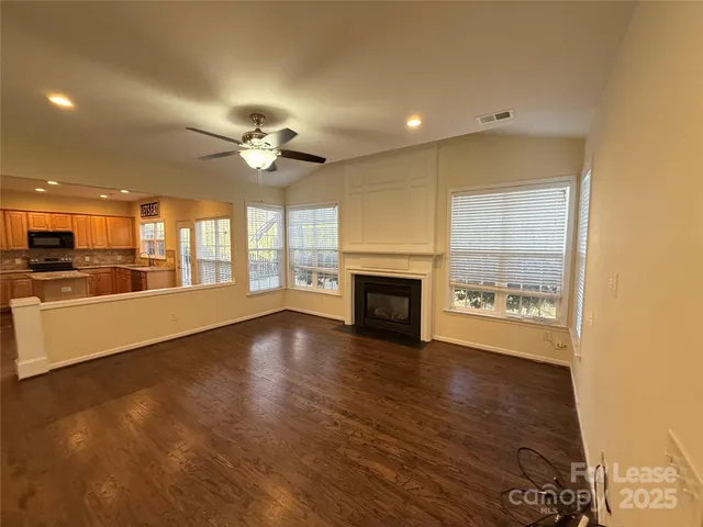 a view of an empty room with a kitchen and a window