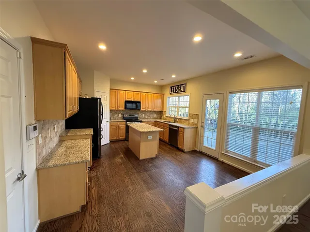 a open kitchen with stainless steel appliances granite countertop a refrigerator a stove and a wooden floors