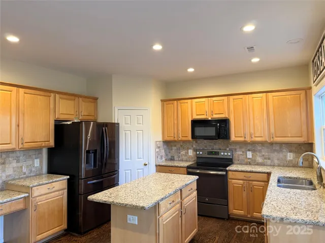 a kitchen with a refrigerator a stove top oven a sink and dishwasher with wooden floor