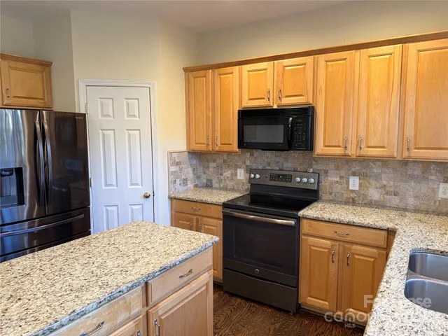 a kitchen with granite countertop wooden cabinets and a stove top oven