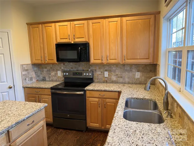 a kitchen with granite countertop a sink stainless steel appliances and cabinets