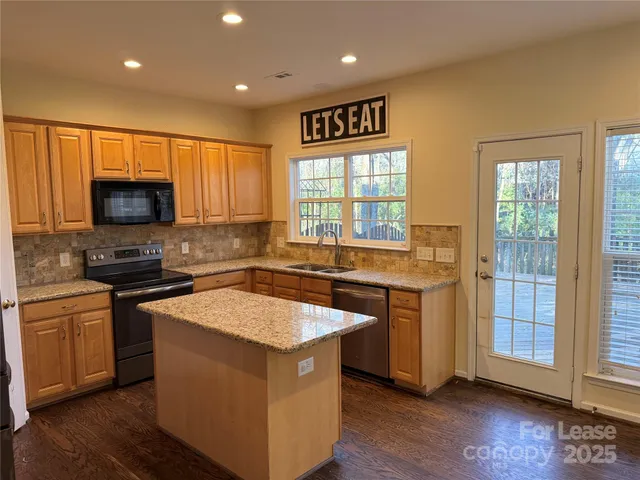 a kitchen with stainless steel appliances granite countertop a stove a sink and a microwave