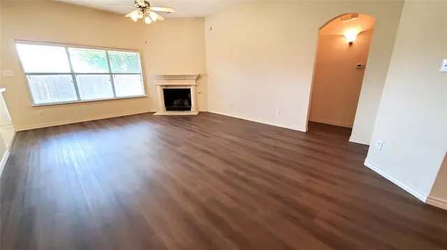 an empty room with wooden floor chandelier and windows