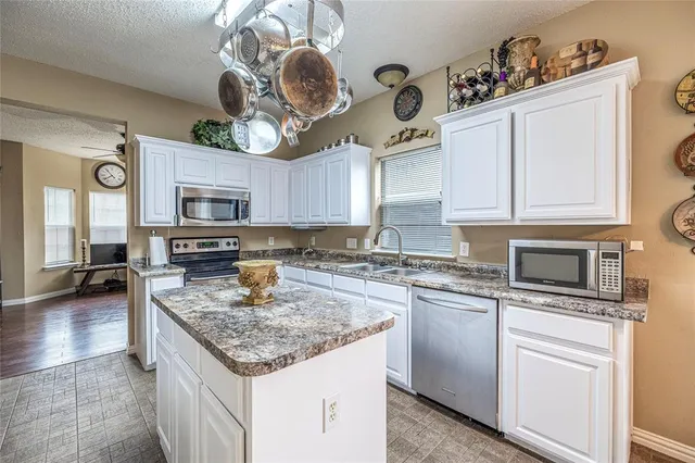 a kitchen with granite countertop stainless steel appliances a stove sink microwave and cabinets