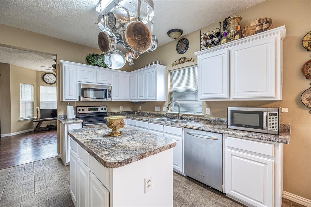 a kitchen with granite countertop stainless steel appliances a stove sink microwave and cabinets