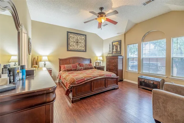 a bedroom with a bed a couch and a large window with wooden floor