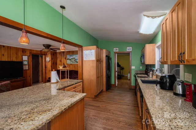 a kitchen with stainless steel appliances granite countertop a refrigerator a stove and a sink with wooden floor