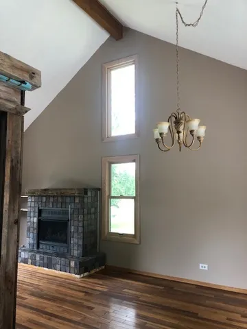 a view of a livingroom with wooden floor a fireplace and windows