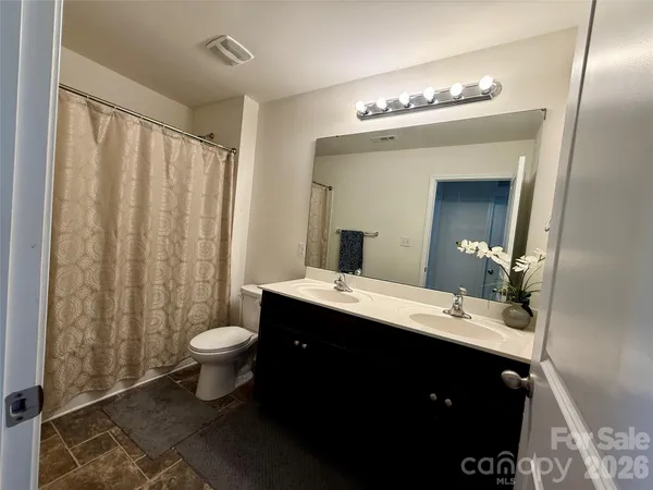 a bathroom with a double vanity sink toilet and a mirror