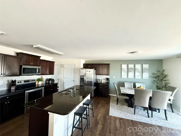 a kitchen with sink refrigerator dining table and chairs