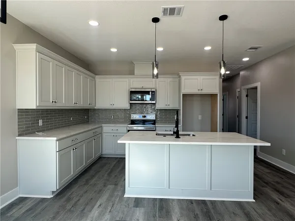 a kitchen with kitchen island a sink stainless steel appliances and cabinets