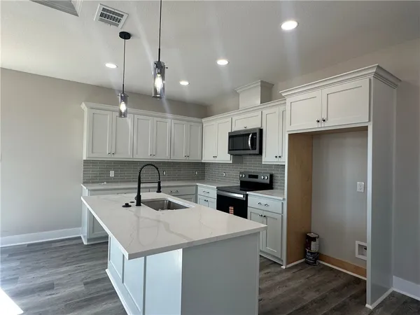 a kitchen with kitchen island a sink stainless steel appliances and cabinets