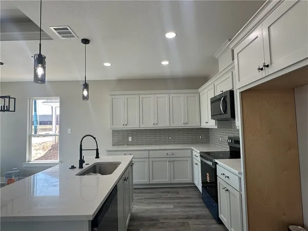a kitchen with white cabinets appliances and a sink