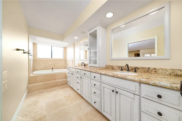 a bathroom with a granite countertop sink mirror and bathtub