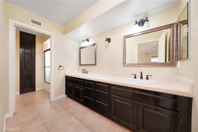 a bathroom with a double vanity sink mirror and bathtub