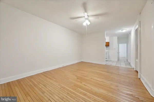 an empty room with wooden floor and fan