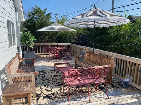 a patio with wooden floor a yard a table and chairs