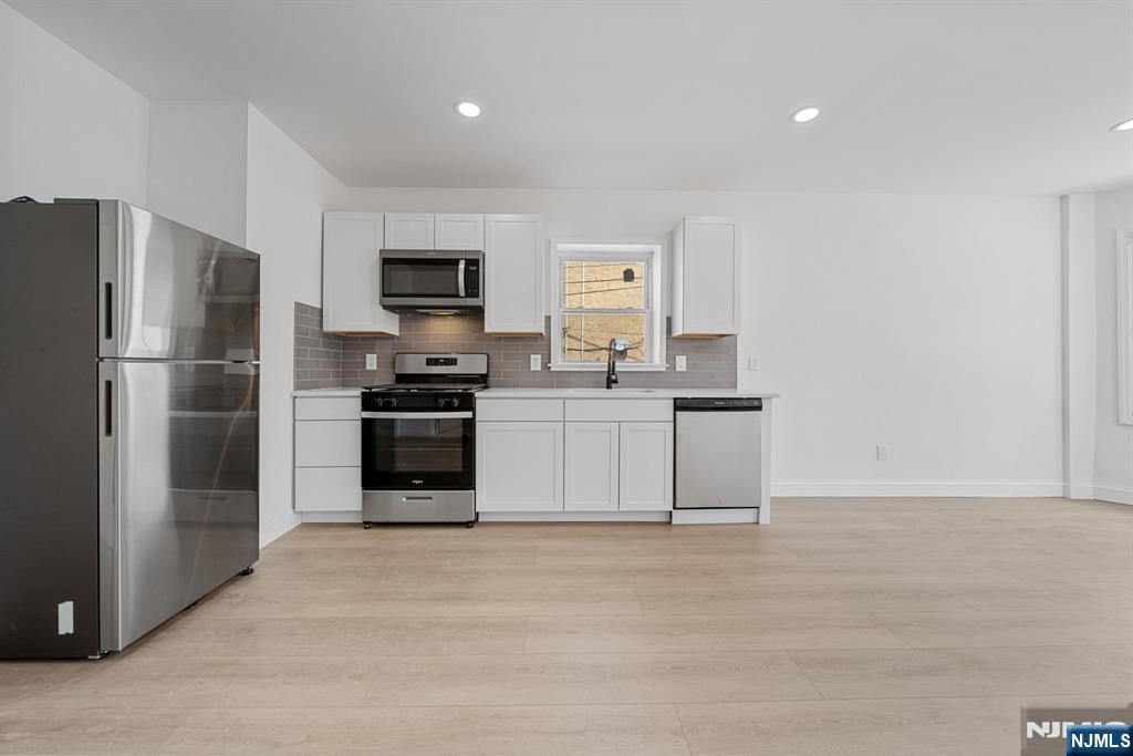 61 Farnham Avenue, Unit 1 Garfield, NJ 07026 - Photo 3 of 14 a kitchen with a refrigerator and a stove top oven